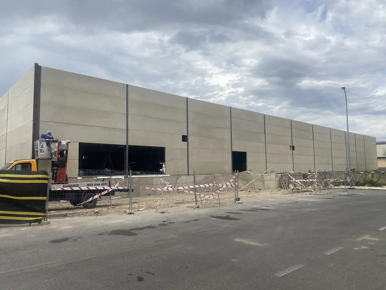 Fachada larga de placas con los huecos de acceso y operarios trabajando