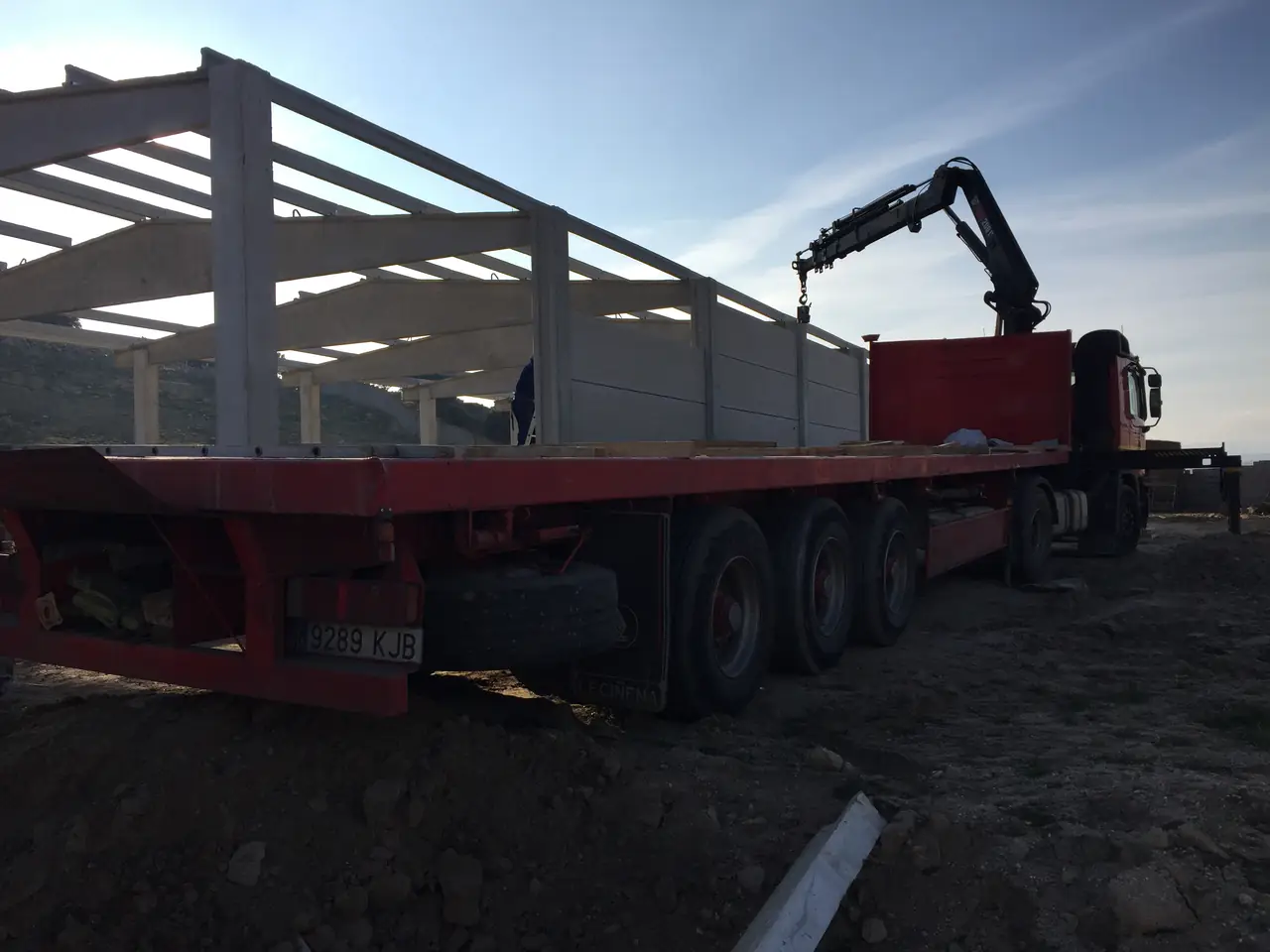 Camión grúa montando placas con la estructura de hormigón al fondo