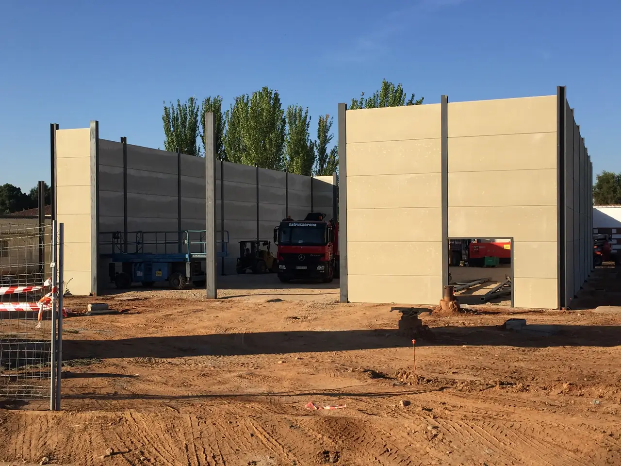 Muros de placas alveolares entre pilares metálicos con el camión grúa de Estrucserena y una plataforma elevadora en el interior