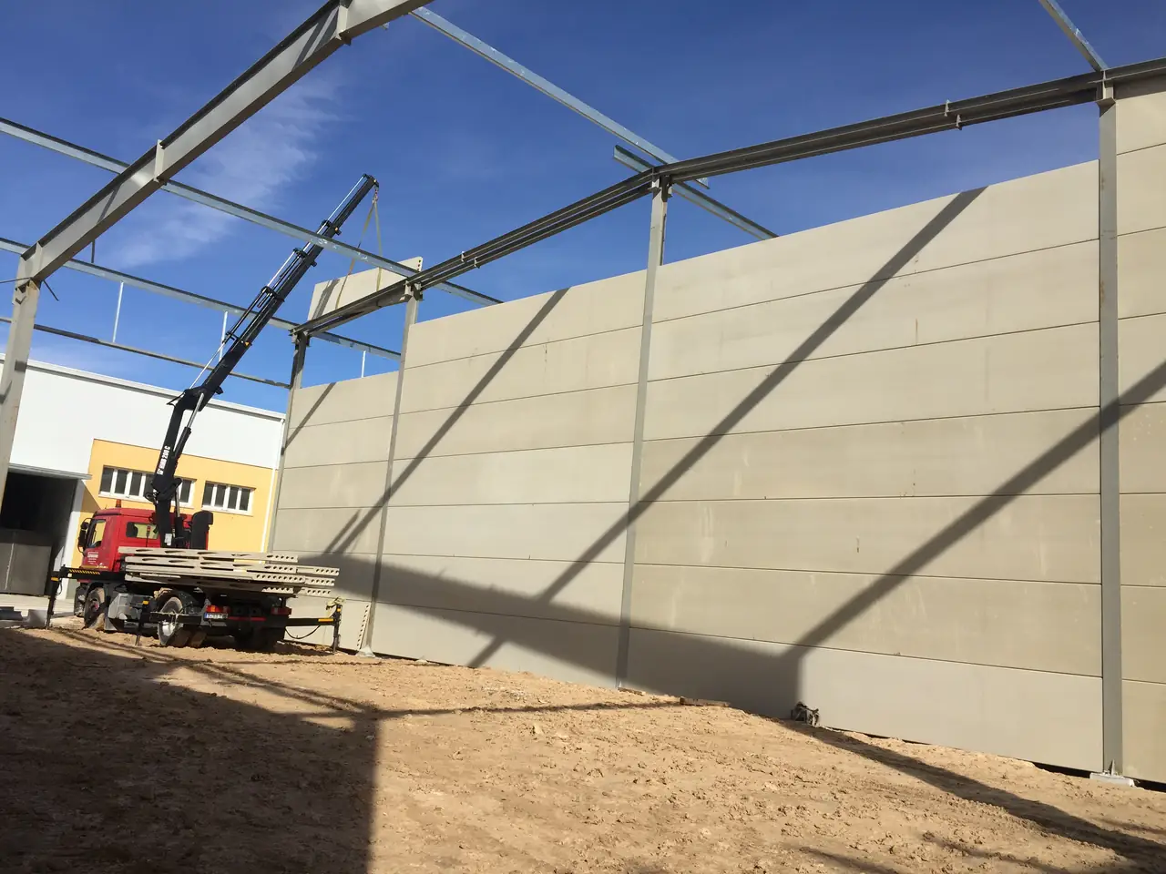 Camión grúa con placas cargadas junto al muro