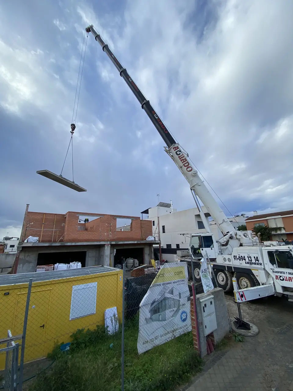 Autogrúa izando una placa junto a la obra