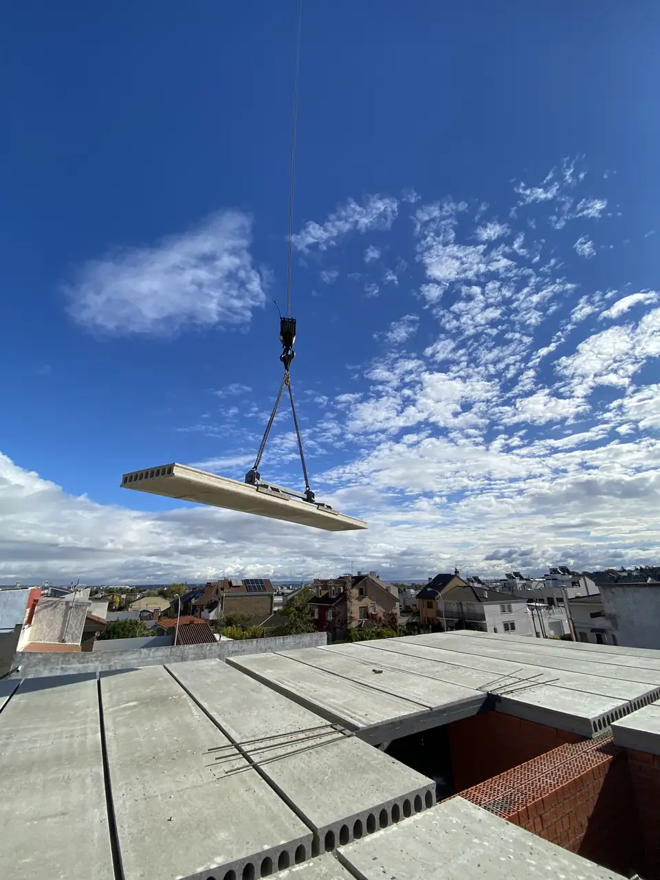 Placa alveolar suspendida de la grúa sobre el forjado ya colocado