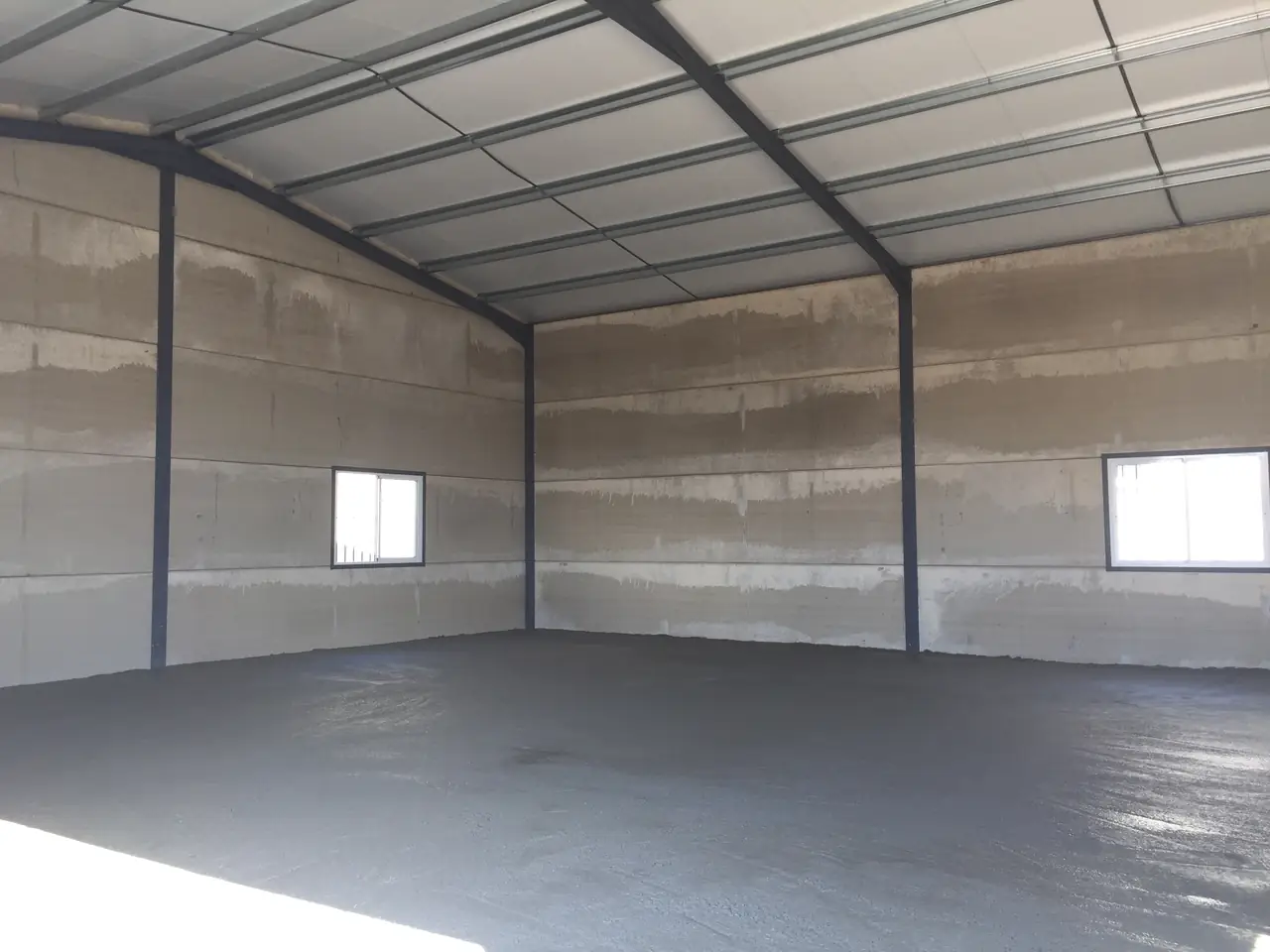Interior de la nave con la estructura metálica, las ventanas y la solera recién hormigonada