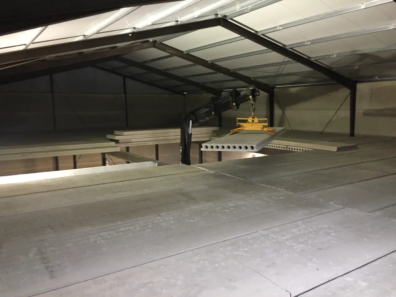 Interior de la nave con el forjado de placas alveolares de la entreplanta y una placa izada por el camión grúa