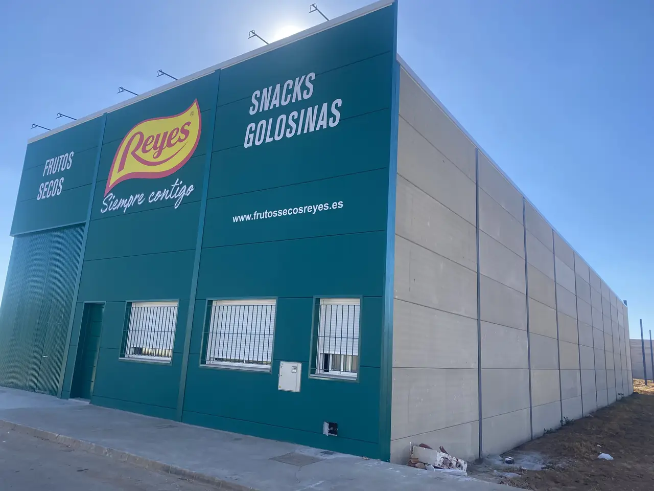 Fachada de la nave con el cerramiento de placas de hormigón y el rótulo del cliente