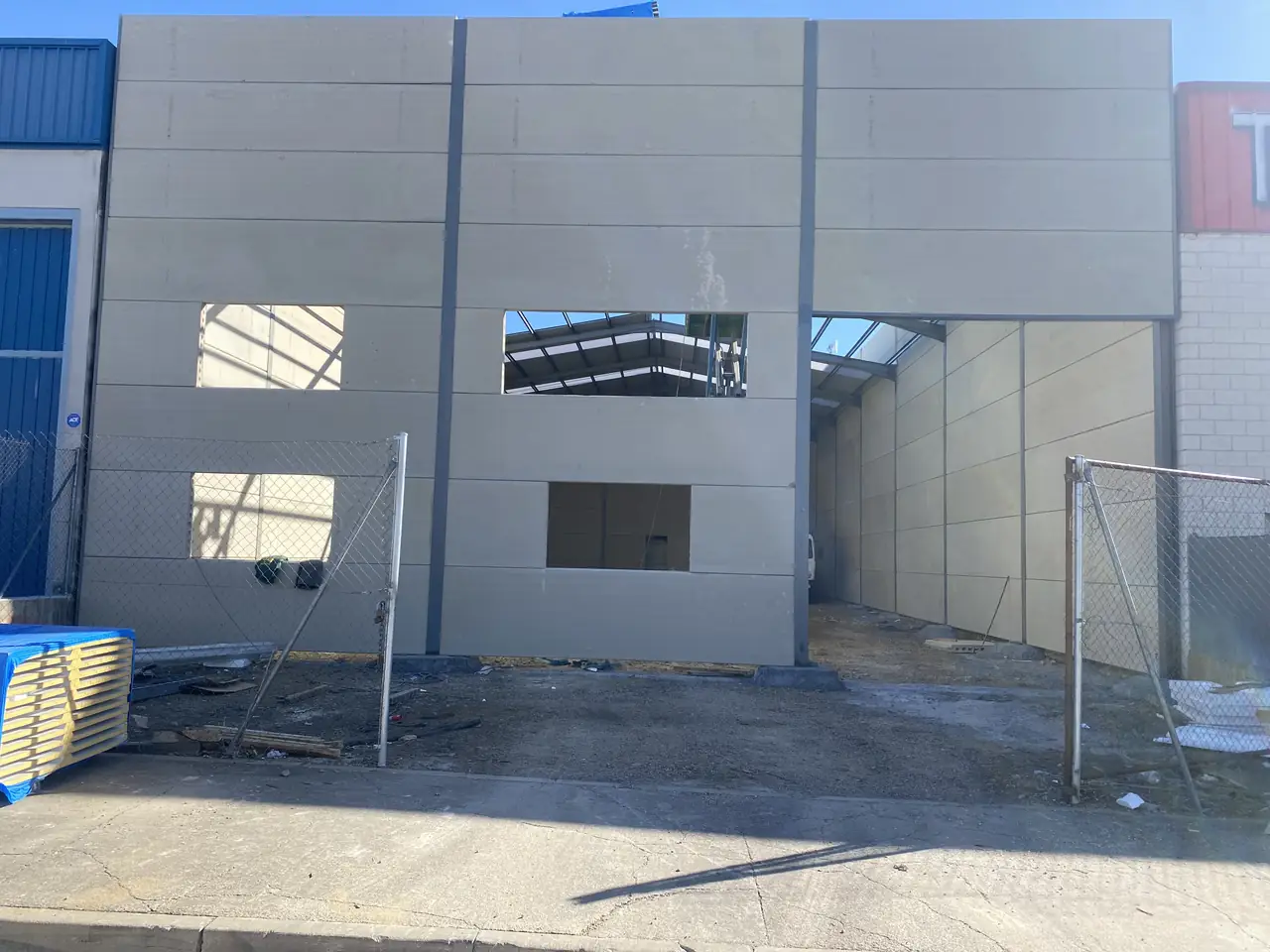Fachada de la nave con el cerramiento de placas, huecos de ventana y acceso